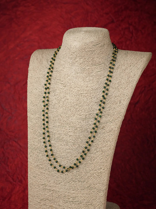 A double-strand beaded necklace with dark green and black beads, displayed on a beige fabric-covered jewelry bust against a textured red background.