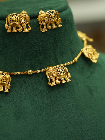 A gold-toned jewelry set featuring elephant-shaped earrings and a matching chain necklace, displayed on a dark green velvet jewelry bust.